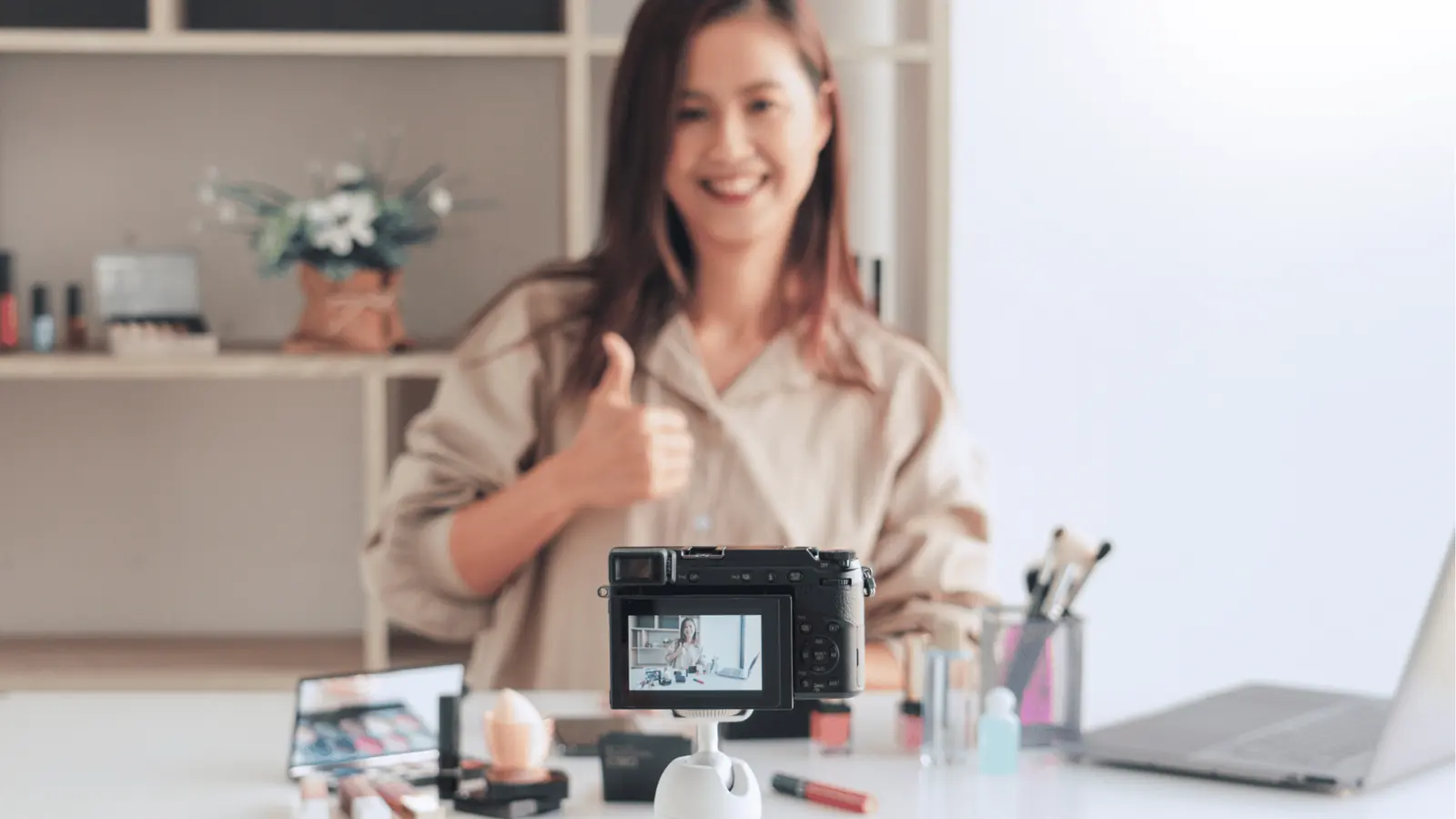 Smiling woman gives thumbs up while recording a makeup tutorial for content calendar