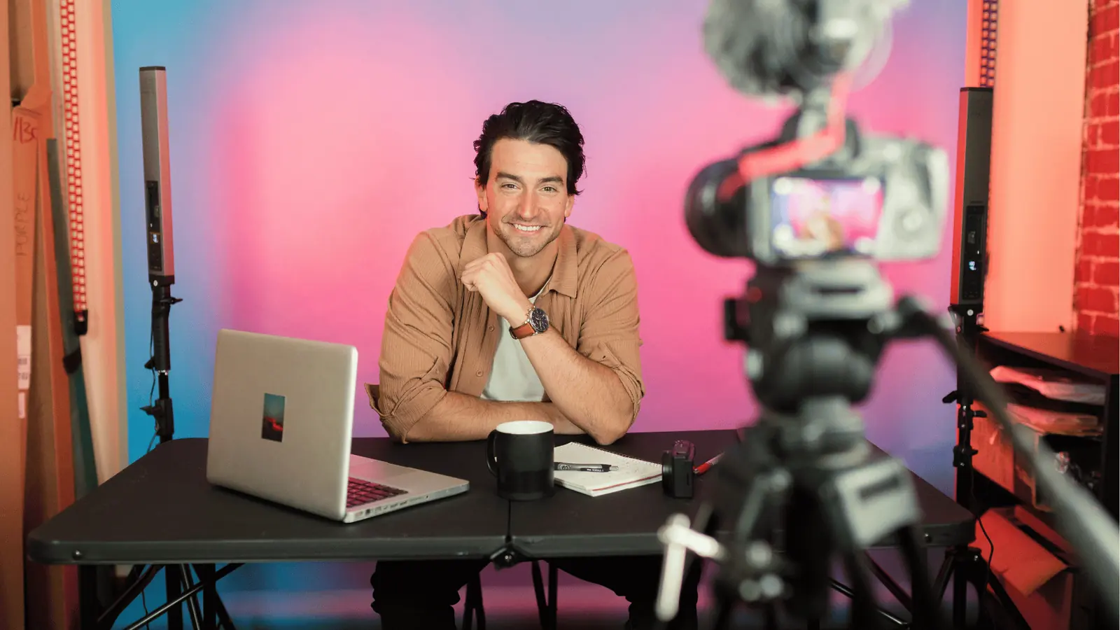 Smiling content creator sits at desk recording a video with camera for inbox management
