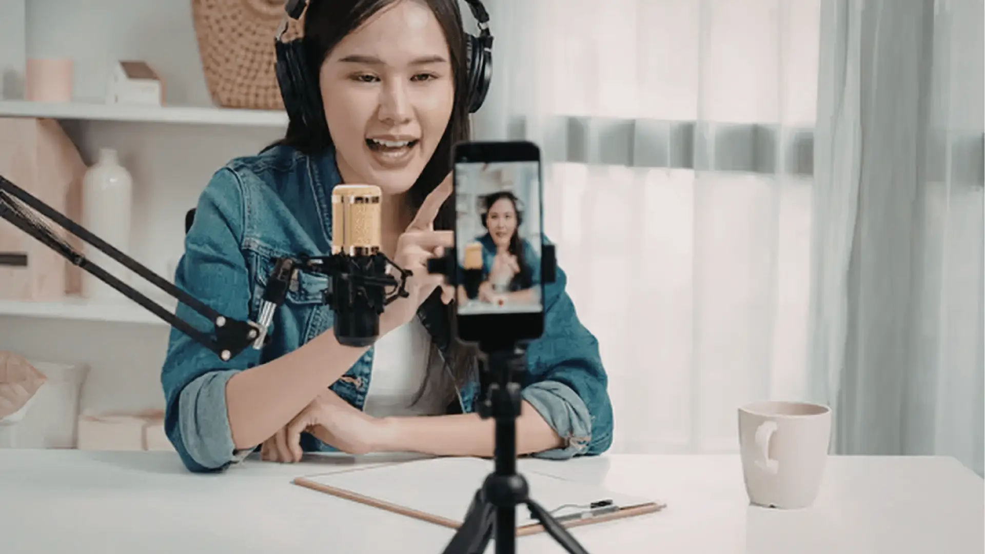 Woman recording a live video on smartphone with microphone and headphones for approval workflow