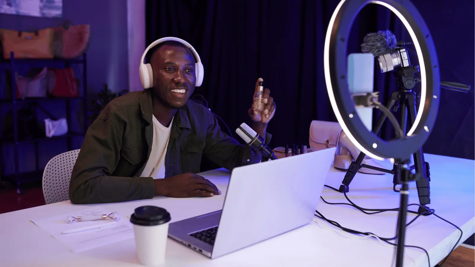 Smiling man with headphones holding a cosmetic bottle during a recording session for automation
