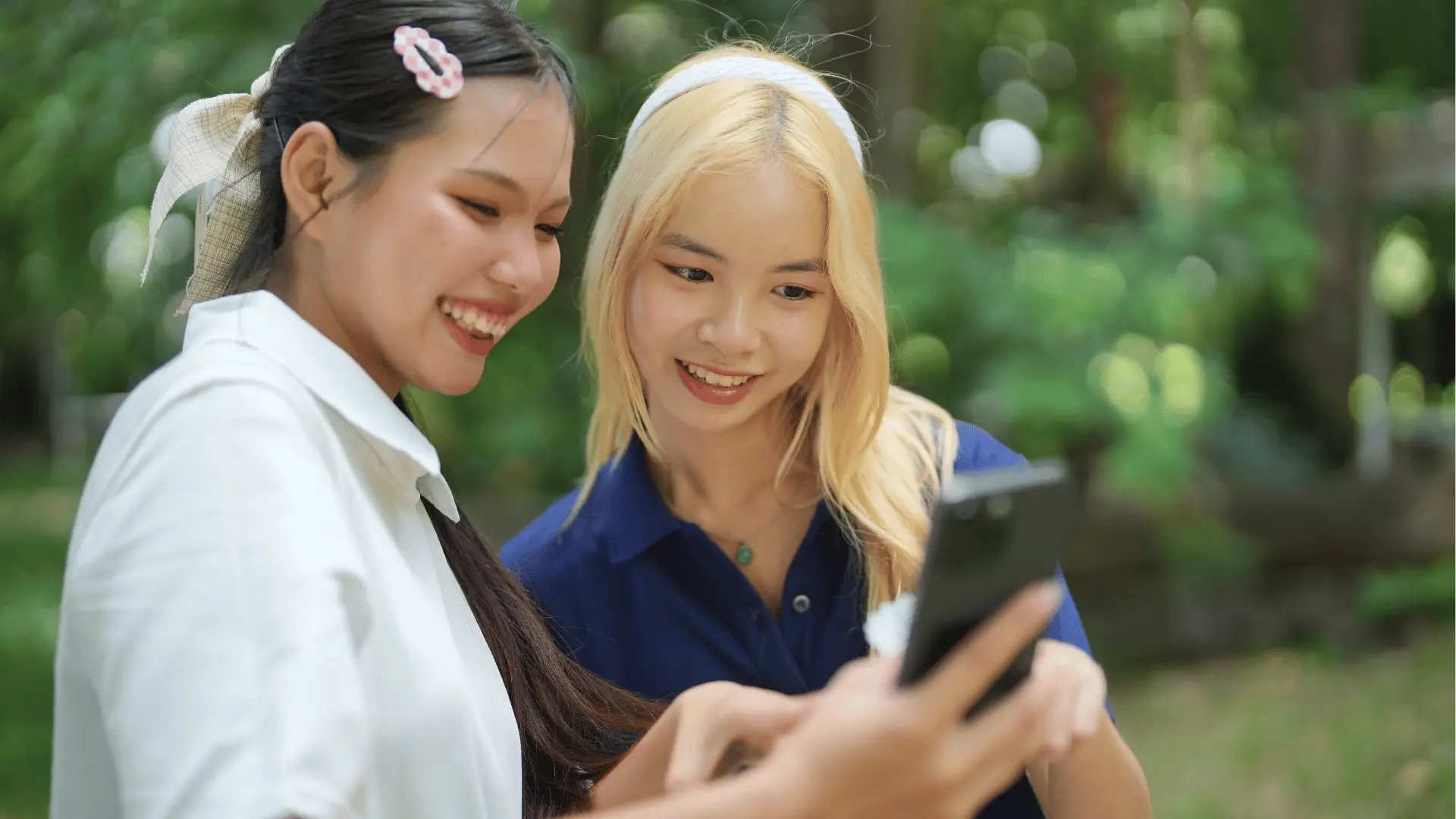 Friends smiling at a phone outdoors