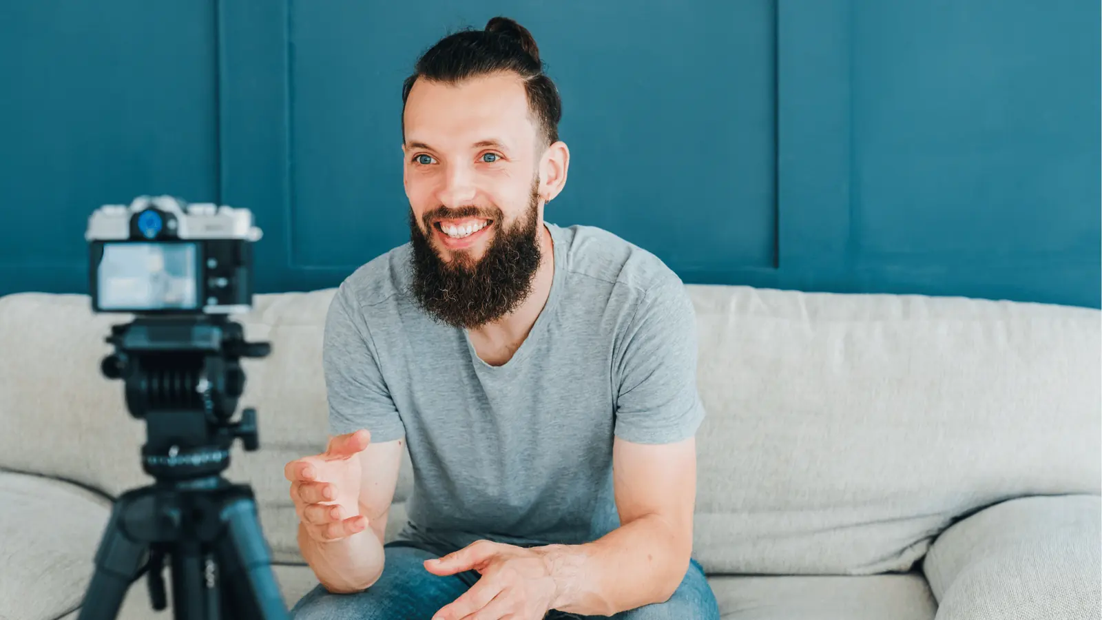 Bearded man sitting on sofa talking to camera mounted on a tripod for community management