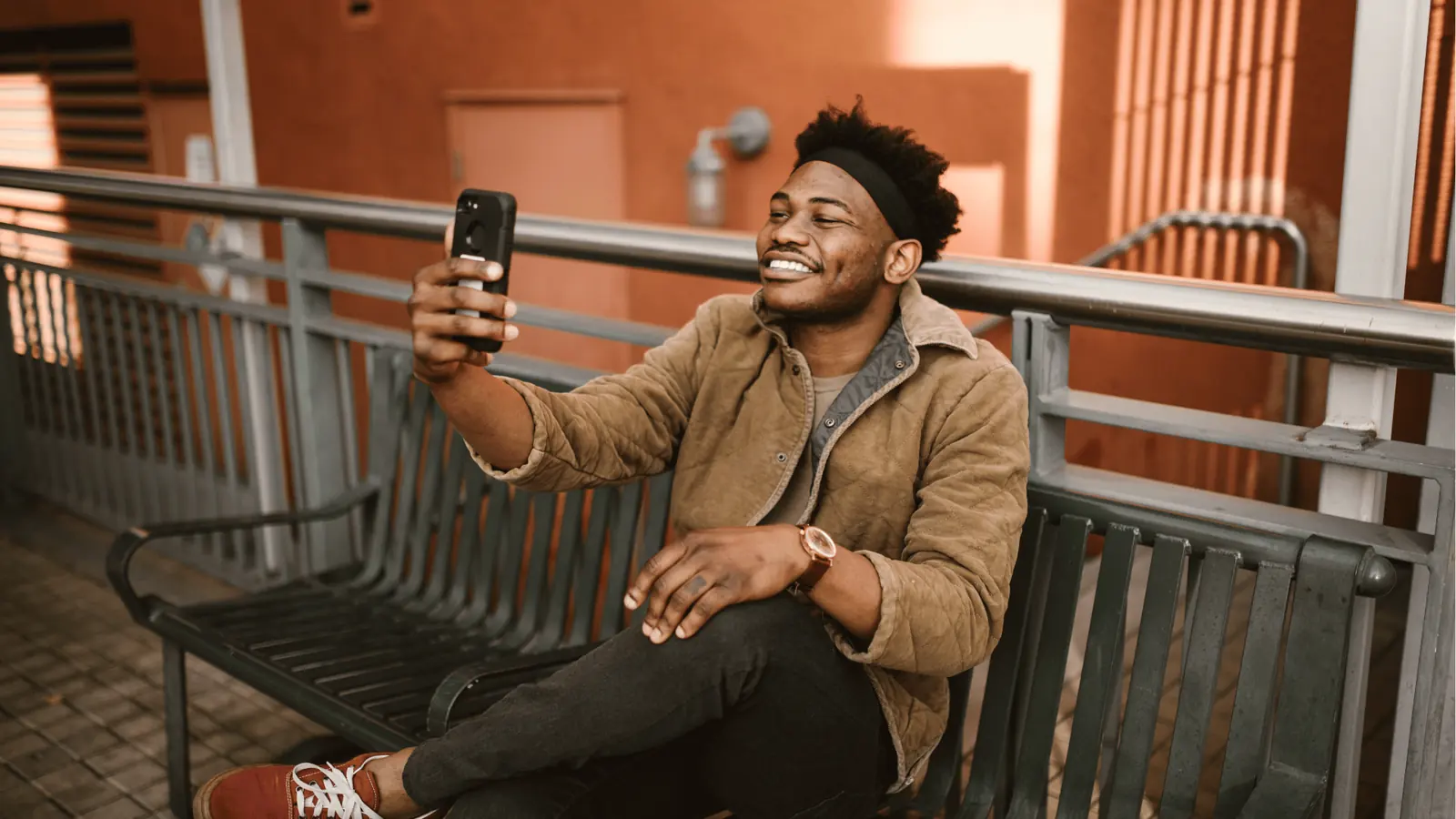 Smiling man taking a selfie on a bench