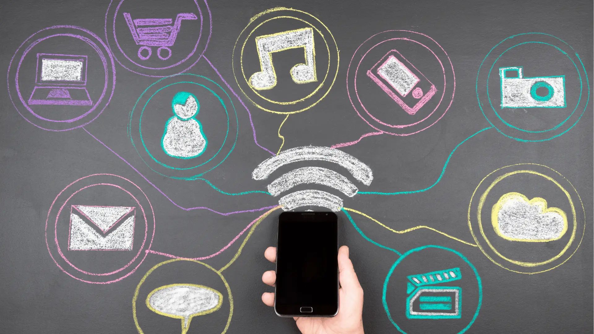 Hand holding smartphone beneath chalkboard app icons and Wi‑Fi signal