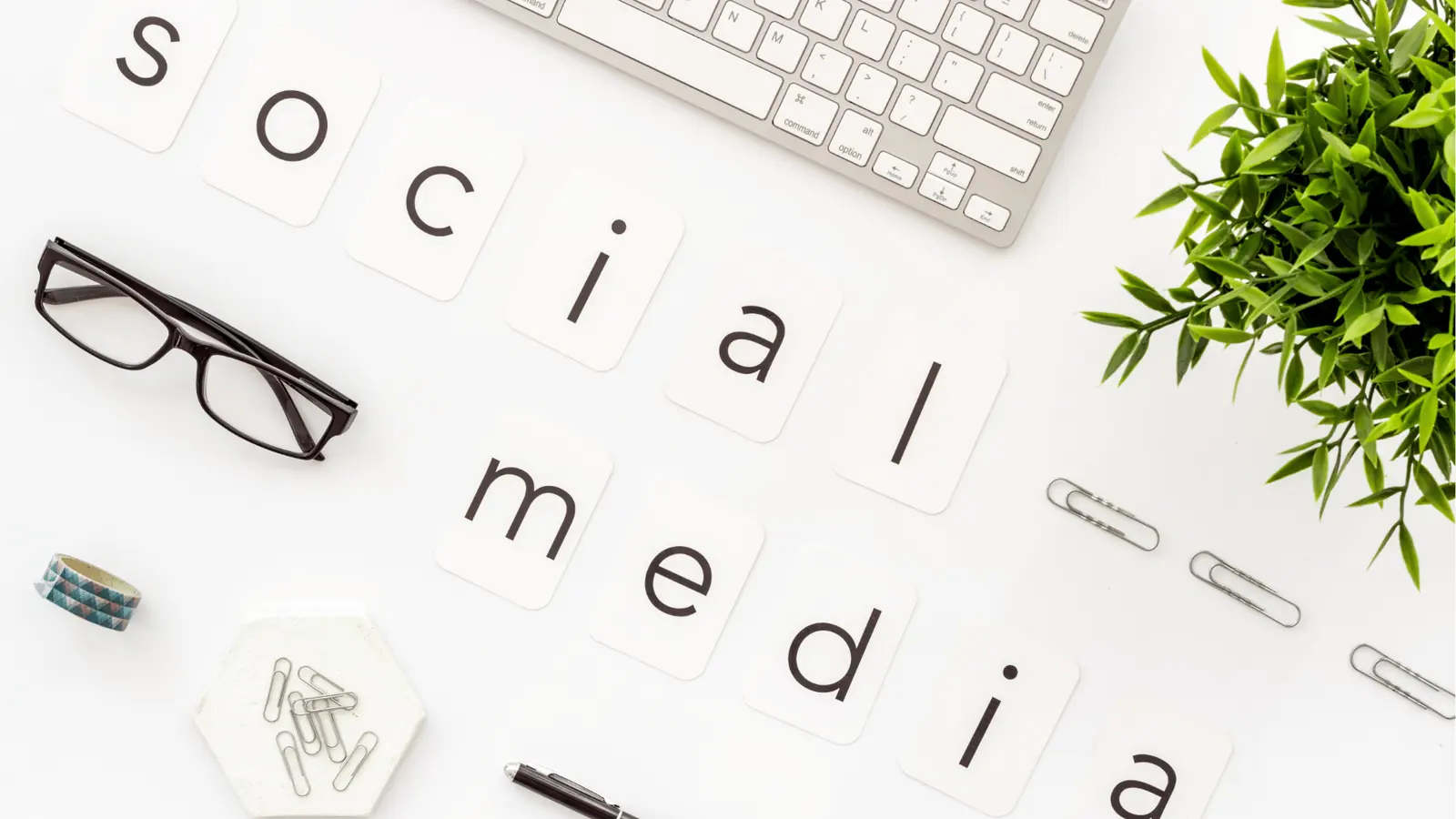 Flat lay desk with letter cards spelling social media and office items for scheduling