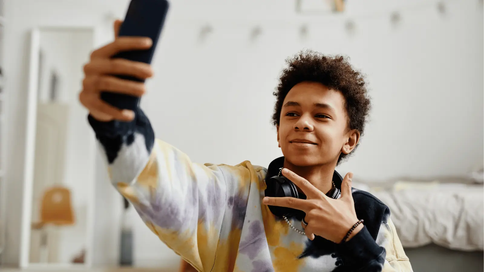 Teenager taking a selfie with headphones around his neck in bedroom for inbox management