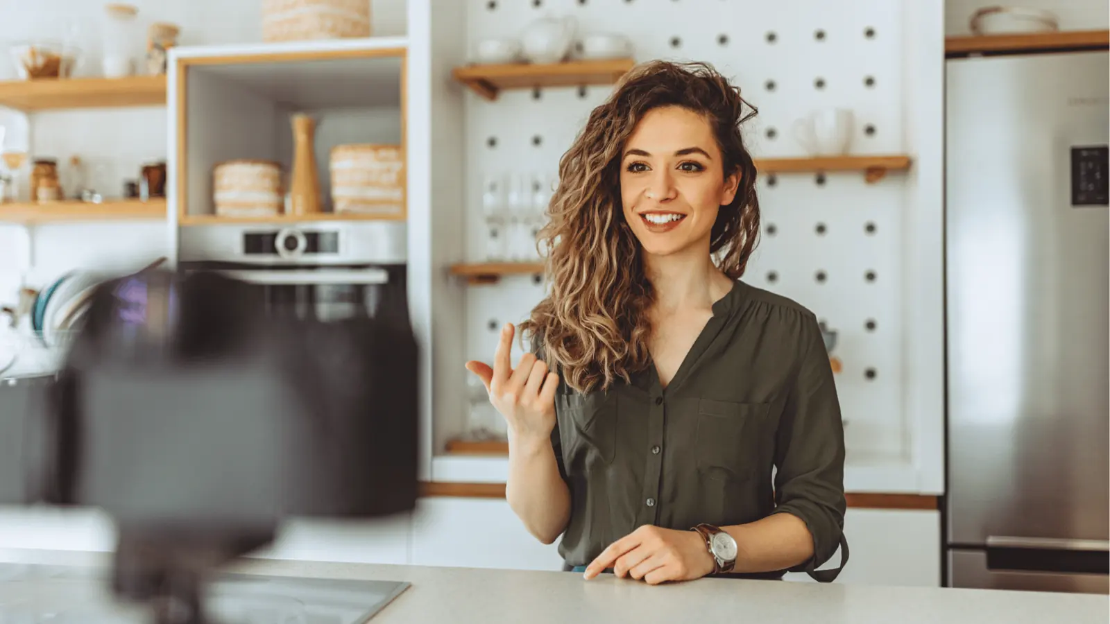 Smiling woman speaking to a camera while standing at a kitchen counter for brand management